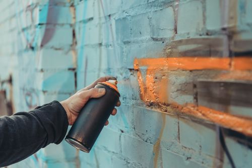 Hand holding a spray can painting a wall