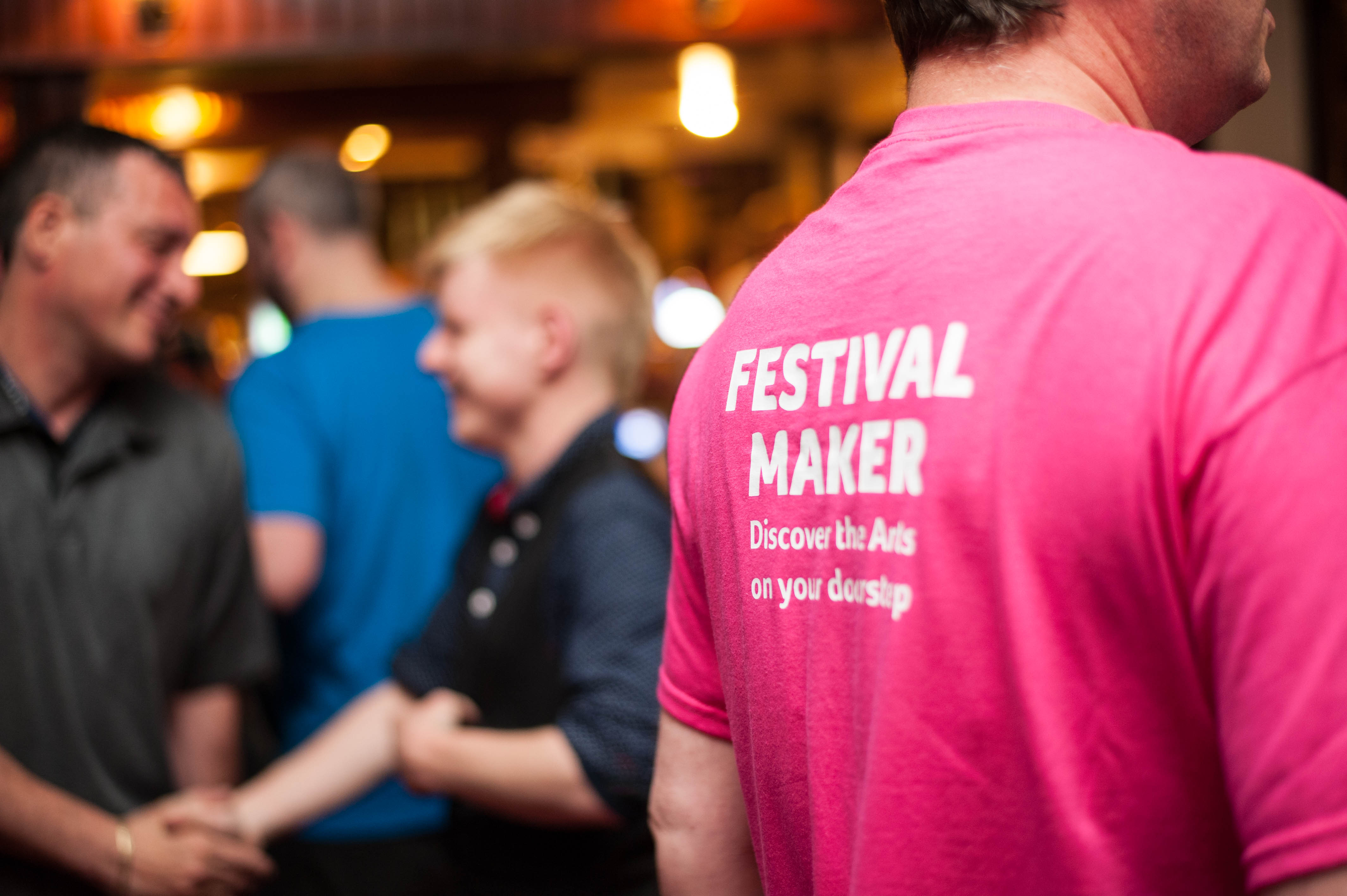 Volunteer in pink t-shirt with back to camera, helping out at an event